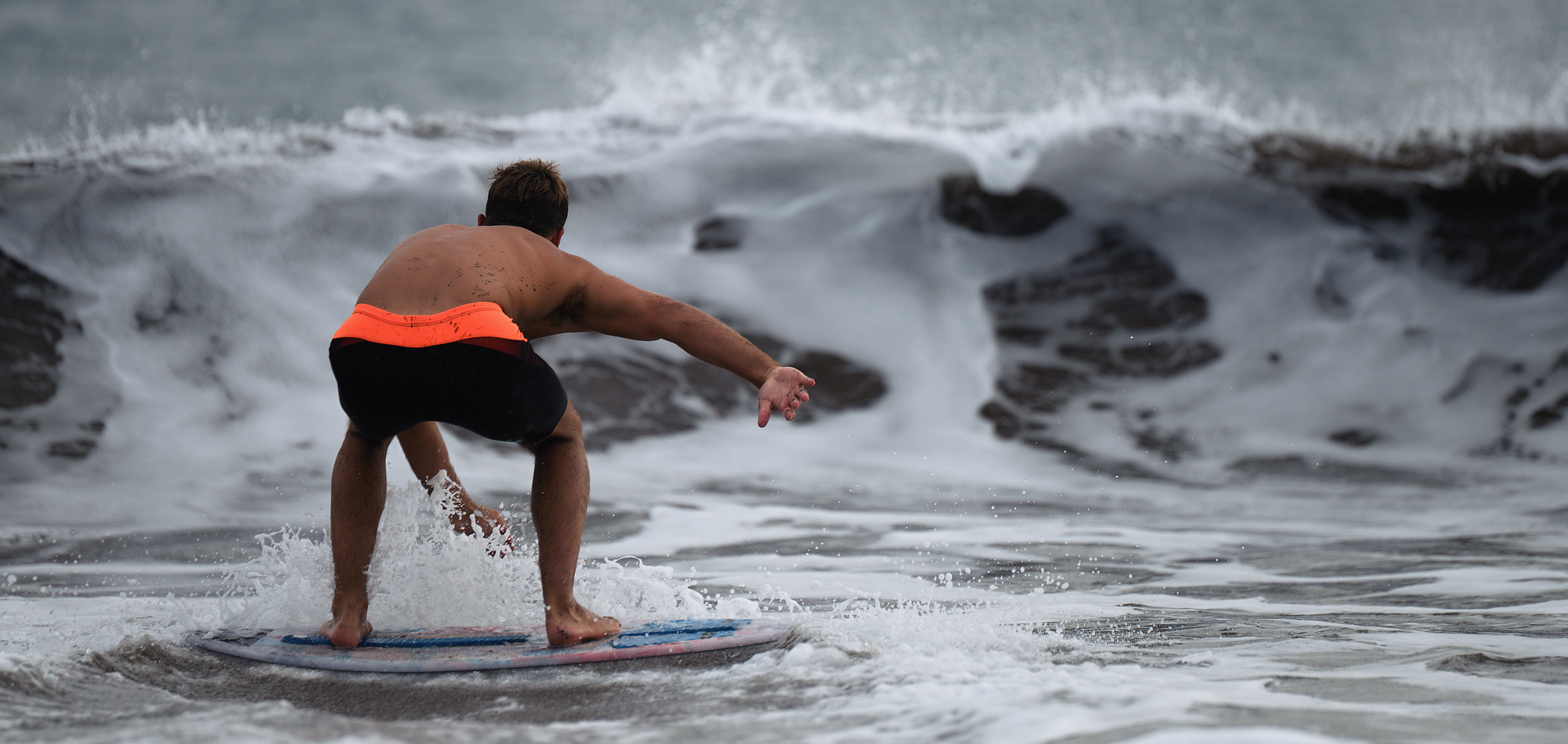 skimboarding approaching wave